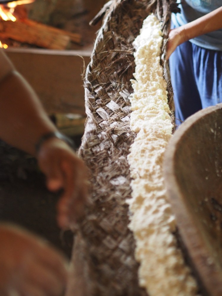 After grating the yucca into a soggy wet pulp, it's laid in this dryer made of woven tree bark, wrapped tight, suspended from the ceiling and twisted really tight, using a stick to get maximum leverage to squeeze the excess liquid out. what remains is almost completely dry. 